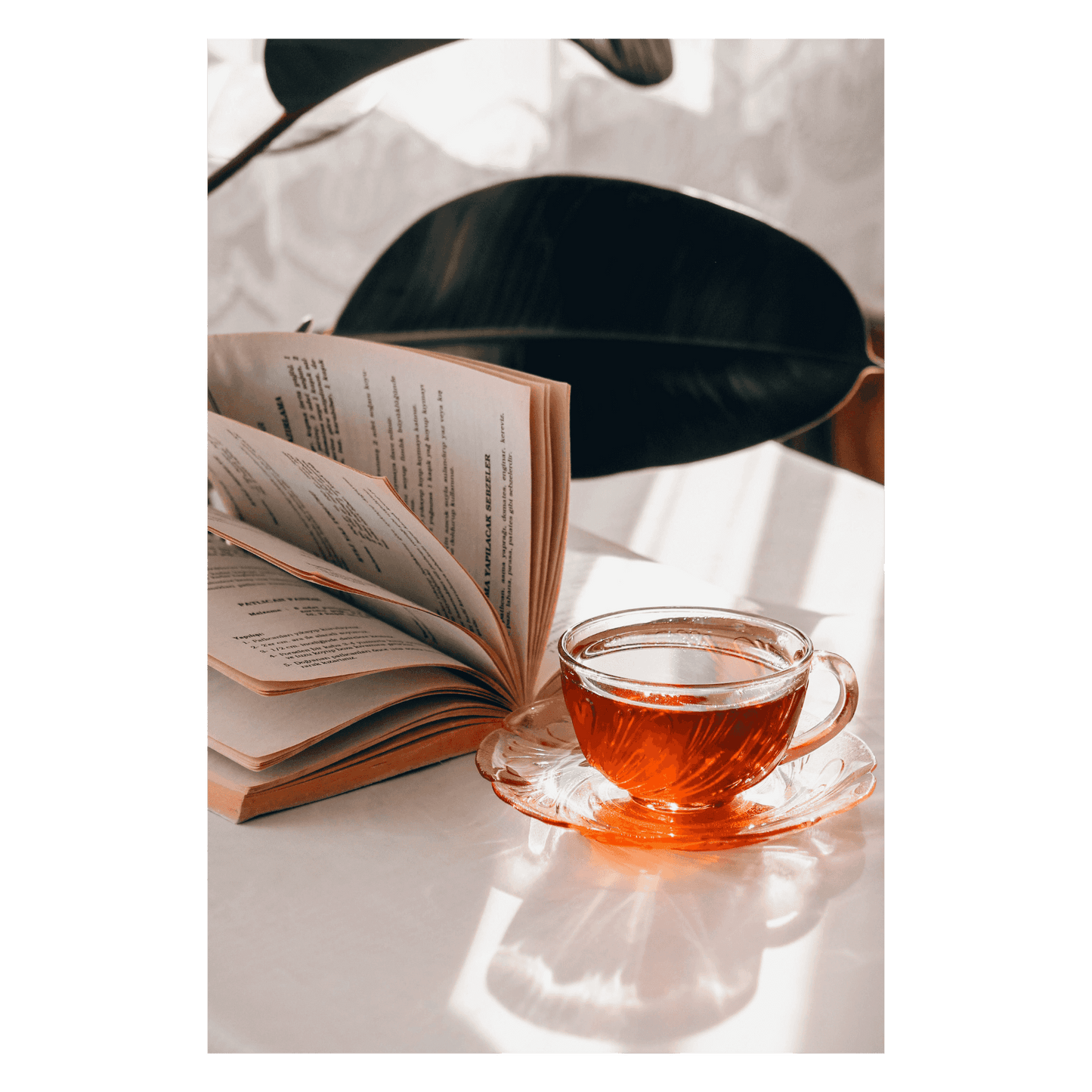 Glass teacup of herbal tea beside an open book, sweetened with Flower Power Botanical Honey, a floral-infused Hawaiian Kiawe honey.